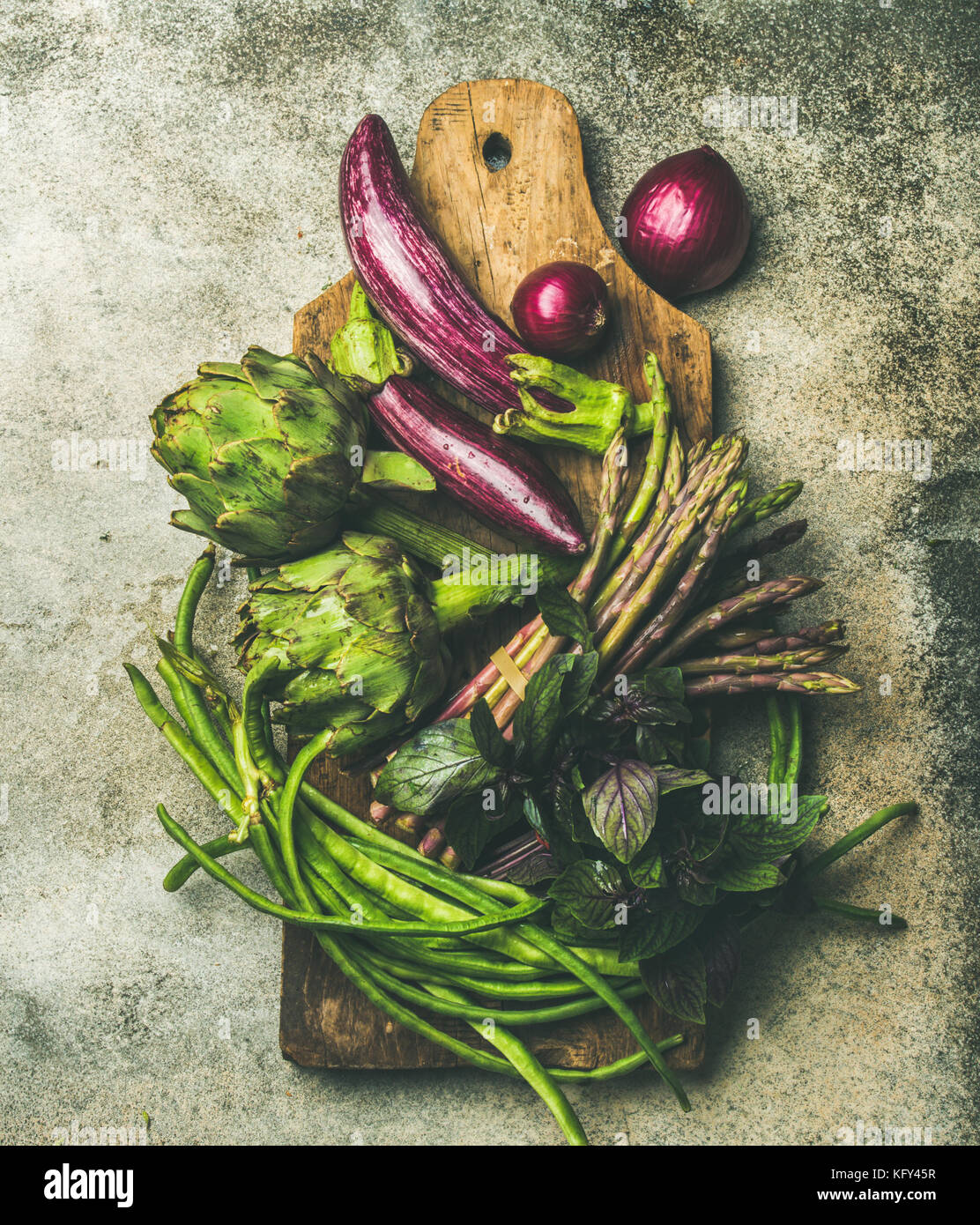 Flachbild-lay von Grün und Violett Gemüse an Bord, grauer Hintergrund Stockfoto