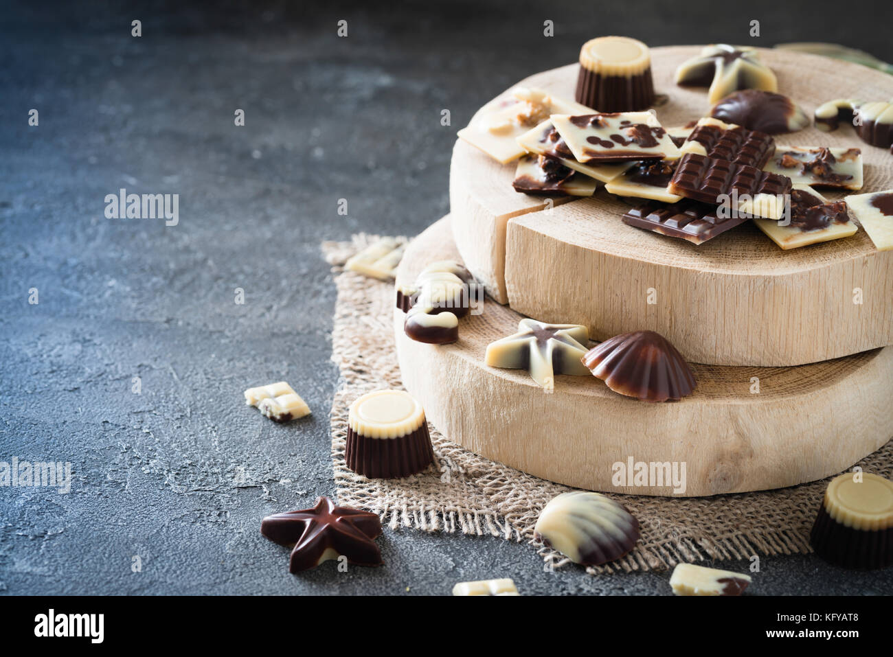 Verschiedene rohe Schokolade Bonbons auf Holzbrett, dunklen Hintergrund. Gesunde Süßigkeiten, kopieren Raum Stockfoto