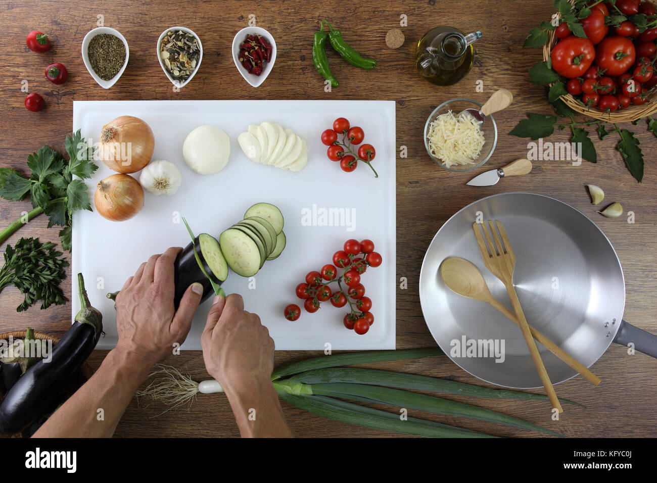 Essen Top View, Hände schneiden Aubergine auf weißen Schneidbrett Küche Holz- Topwork mit Tomaten, Gemüse und Topf Stockfoto