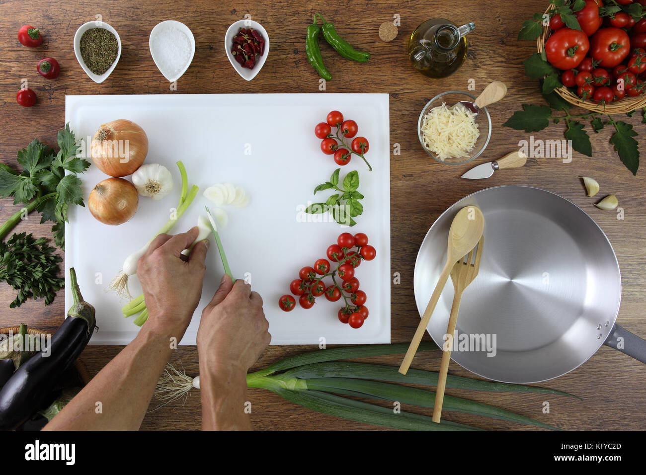 Essen Top View, Hände schneiden grüne Zwiebel auf weißem Schneidbrett Küche Holz- Topwork mit Tomaten, Gemüse und Topf Stockfoto