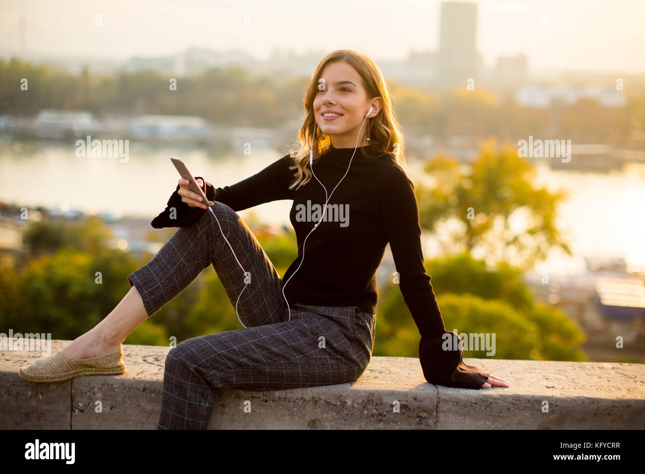 Trendige junge Frau hört Musik von Smartphone outdoor bei Sonnenuntergang Stockfoto
