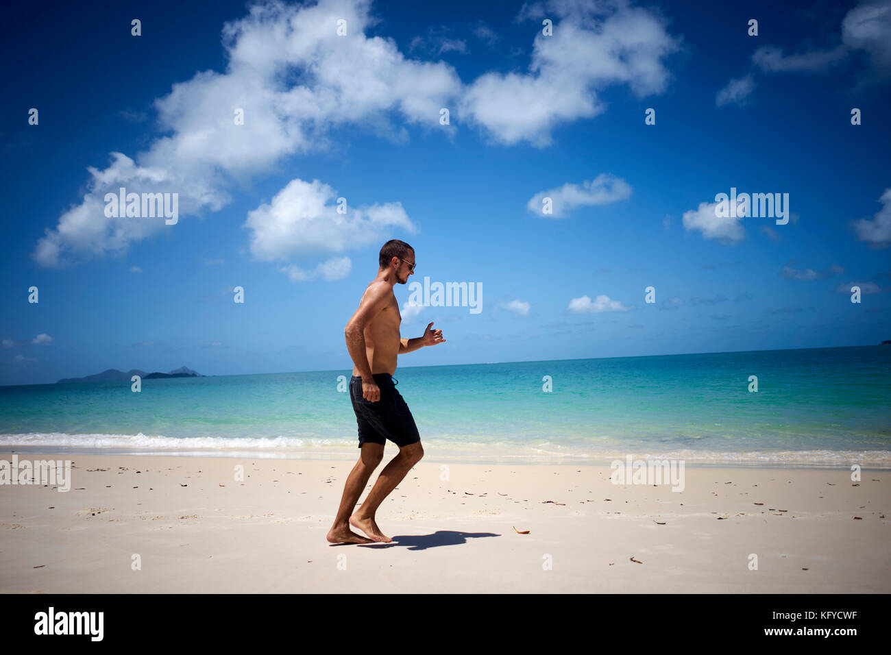 Junge gut ausgebildete Menschen läuft am Strand entlang in Badeshorts Stockfoto