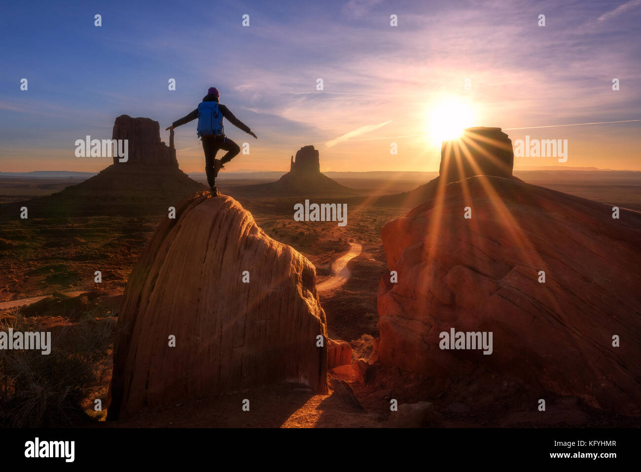 Sonnenaufgang im Monument Valley, Arizona - Utah State Line. Ein reisender Mann express Freiheit Emotion auf einem großen Felsen ant die Handschuhe. Stockfoto