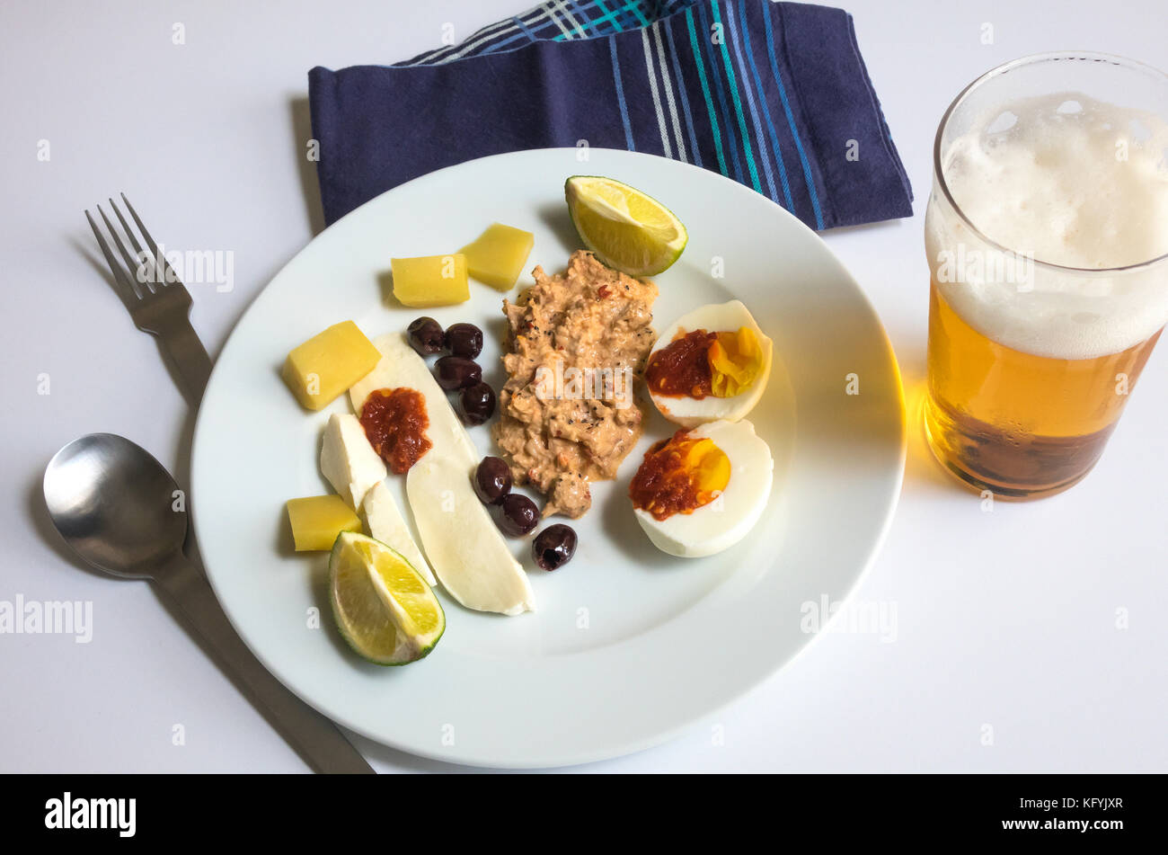Einen kalten Sommer Mittagessen, mit Thunfisch Salat, einer würzigen, hartgekochte Eier, Oliven, Mozzarella, Cheddar, Kalk und Pint ofa größere Bier Stockfoto