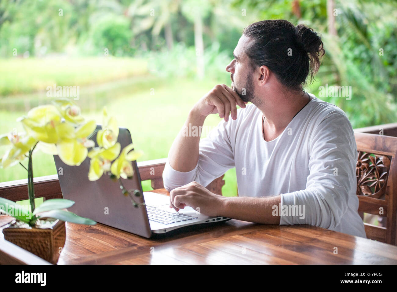 Freiberufliche Arbeit am Laptop. legerer Mann am Schreibtisch aus Holz im Garten sitzen, Arbeiten am Computer gekleidet Stockfoto