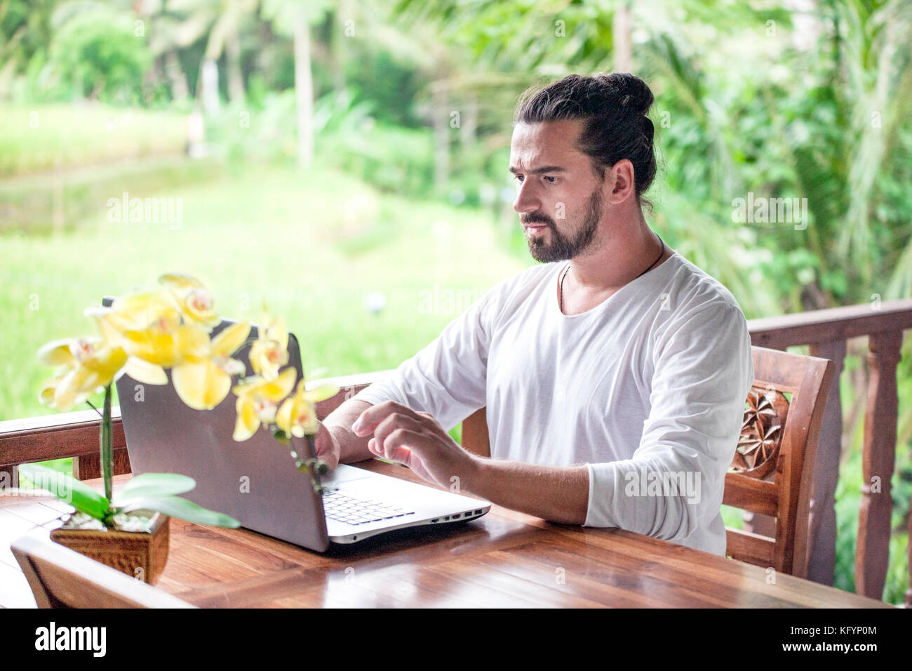Freiberufliche Arbeit am Laptop. legerer Mann am Schreibtisch aus Holz im Garten sitzen, Arbeiten am Computer gekleidet Stockfoto