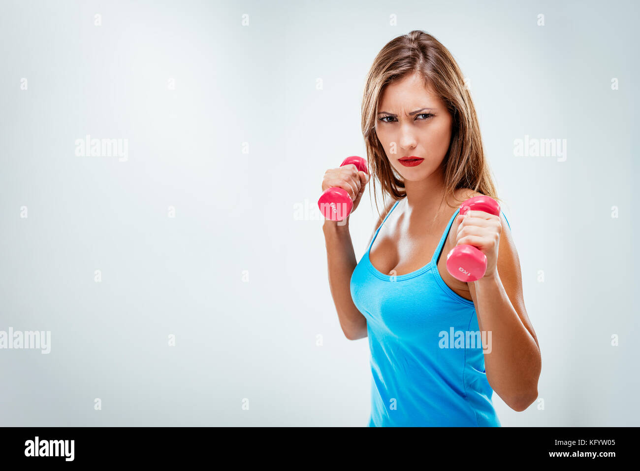 Schöne fitness Frau mit ernsten Gesicht, übung Training arme Hanteln. auf weißem Hintergrund. Stockfoto