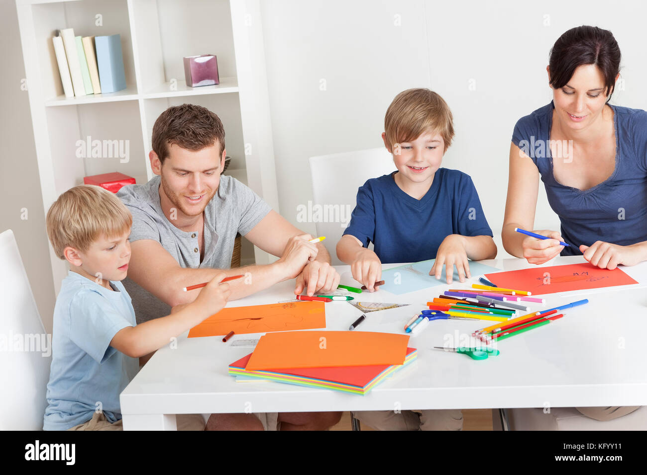 Junge Familie zeichnen zusammen mit bunten Bleistiften zu Hause Stockfoto