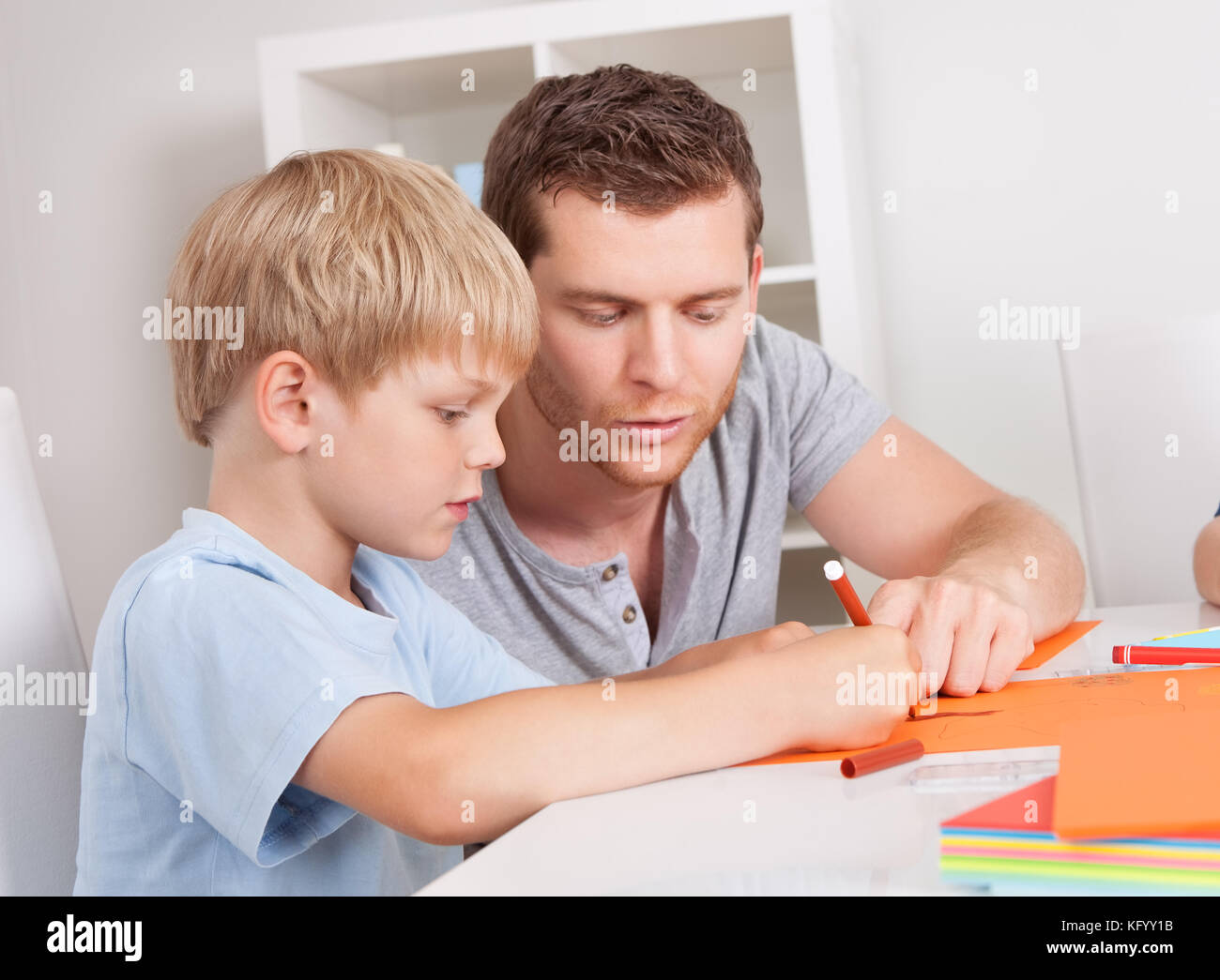 Junge Familie zeichnen zusammen mit bunten Bleistiften zu Hause Stockfoto
