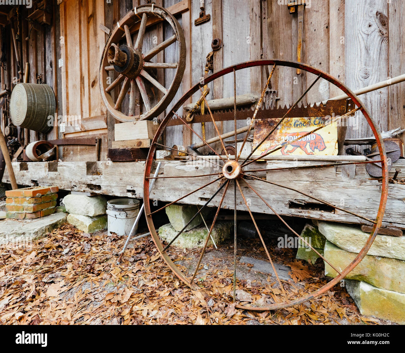 Antike Bügeleisen Wagenrad und hölzernen Wagen Rad hinter alten Holzhütte in ländlichen Alabama, USA verworfen. Stockfoto
