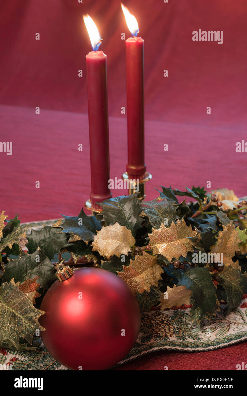 Weihnachtstabelle Dekoration mit Kerzen Holly und rote Kugel ornament Stockfoto