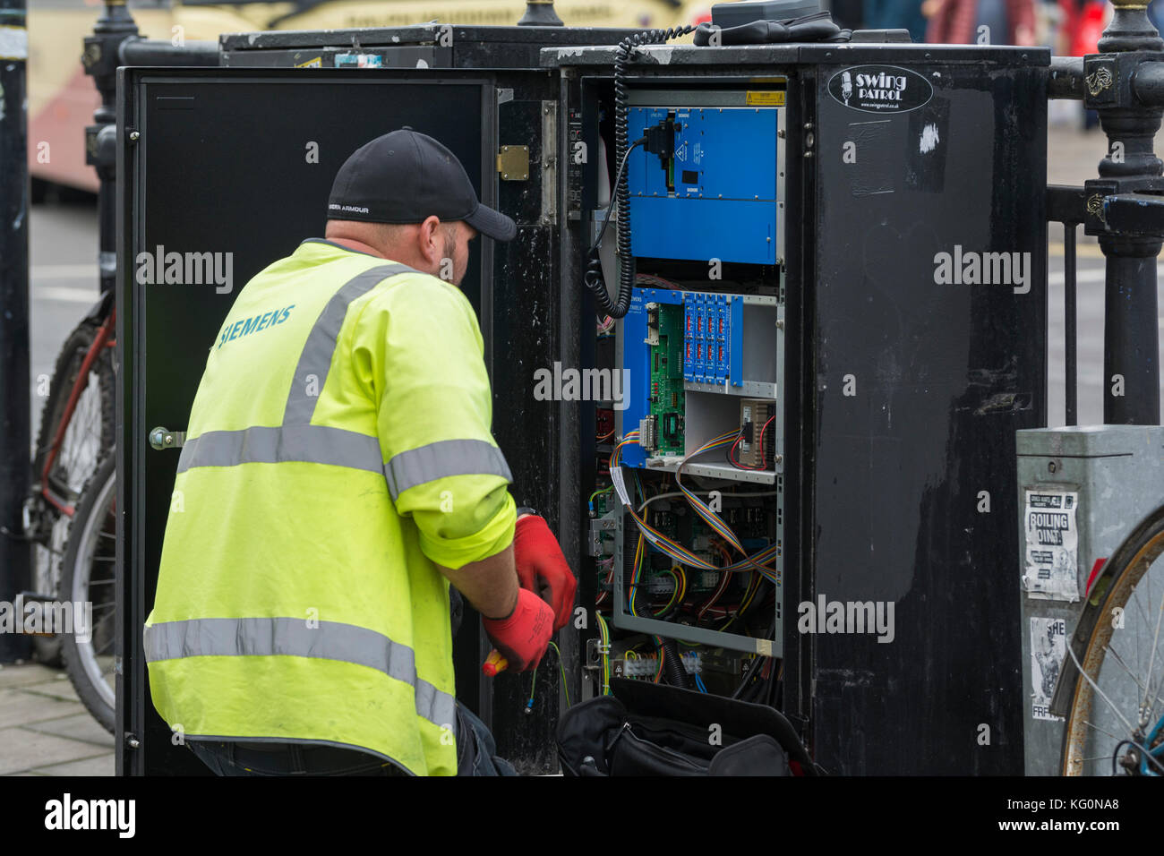 Siemens-Mitarbeiter, der Wartungsarbeiten an einem Kommunikationsschrank in der Straße in Großbritannien durchführt. Stockfoto