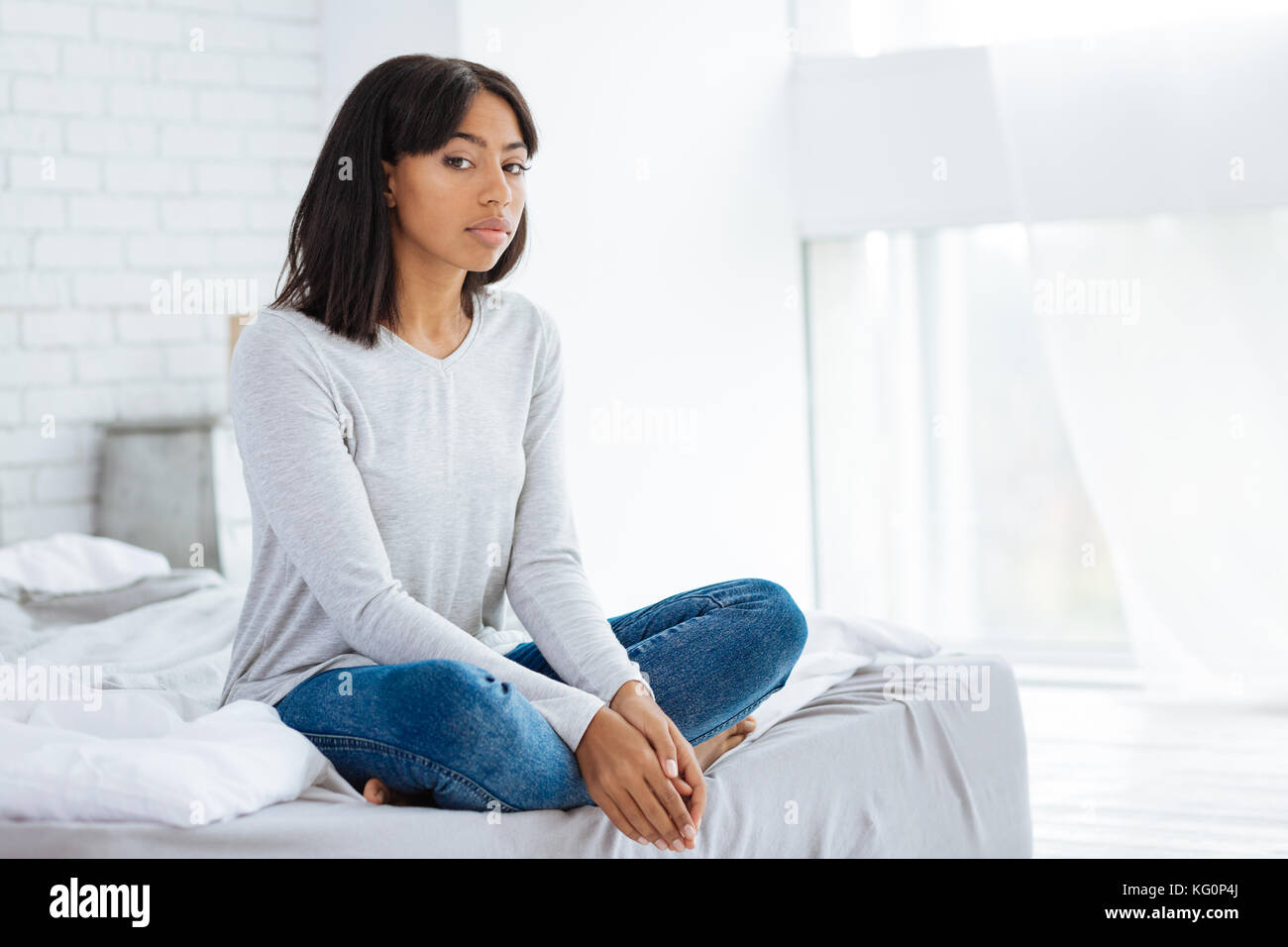 Entspannt junge Frau sitzt auf dem Bett Stockfoto