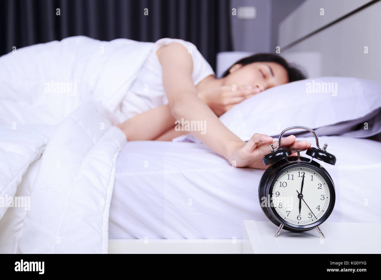 Frau gieren auf dem Bett und steigen an Wecker im Schlafzimmer drehen Stockfoto