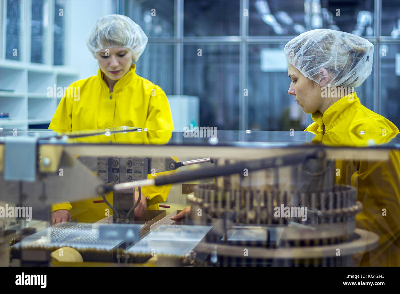 Medizinische Impfstoff Fertigung. weibliche Arbeitnehmer neben Ampulle optische inspetion Maschine an den pharmazeutischen Fabrik. Stockfoto