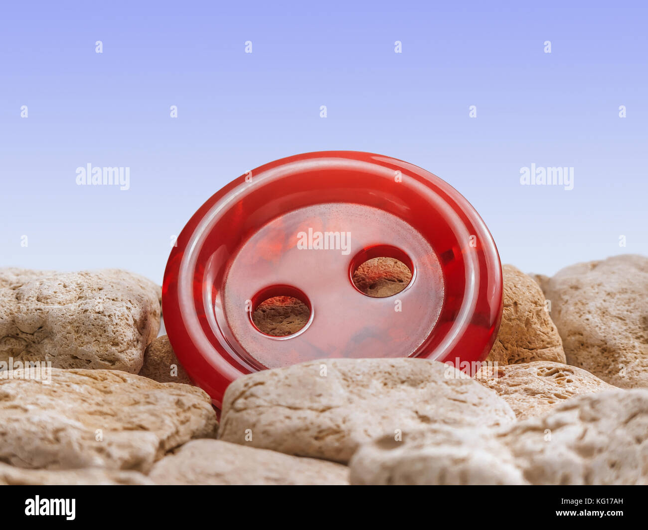 Helle rote Taste unter den Steinen mit blauen Gradienten Hintergrund. Stockfoto