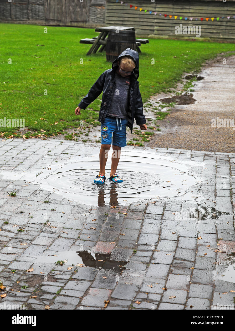 Ein Junge spielt in einer Pfütze gebildet nach starkem Regen Stockfoto
