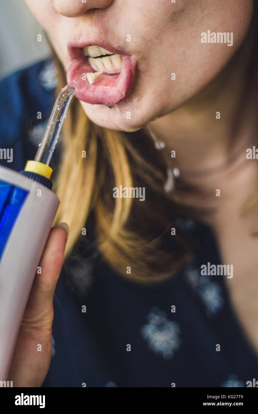 Eine Frau mit einem mundirrigator im Badezimmer. Stockfoto