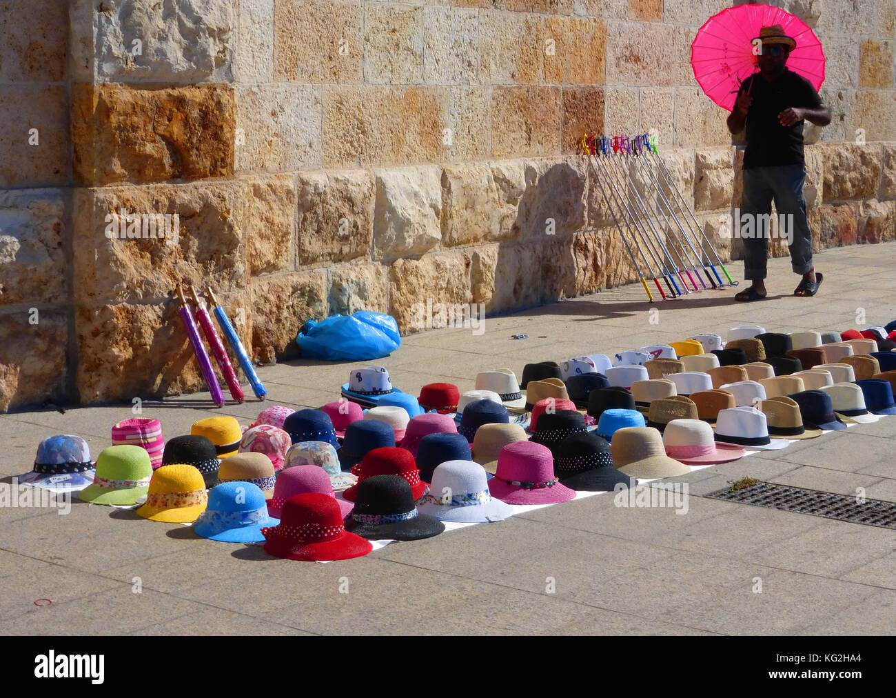 Mann mit roten Sonnenschirm Verkauf von Sun - Hüte in der Straße, Cagliari, Sardinien, Italien Stockfoto