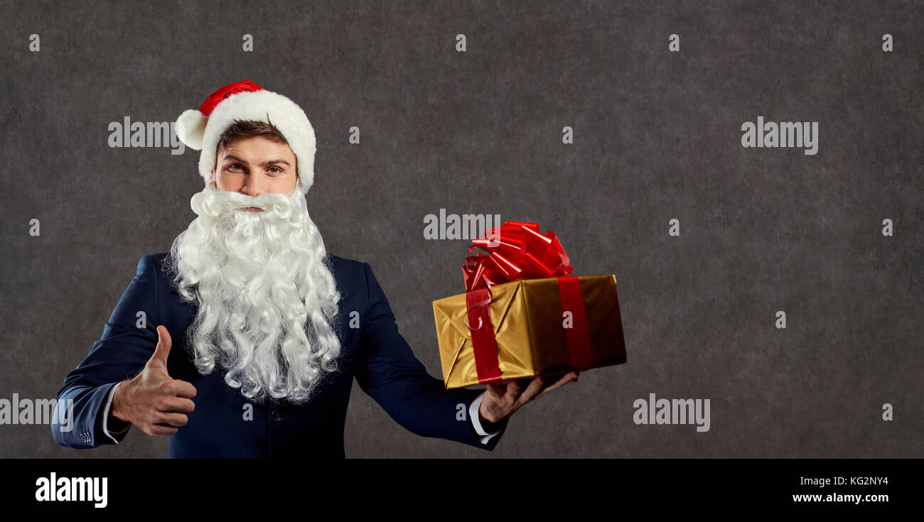 Geschäftsmann in santa claus Kostüm mit einem Geschenk in der Hand. Stockfoto