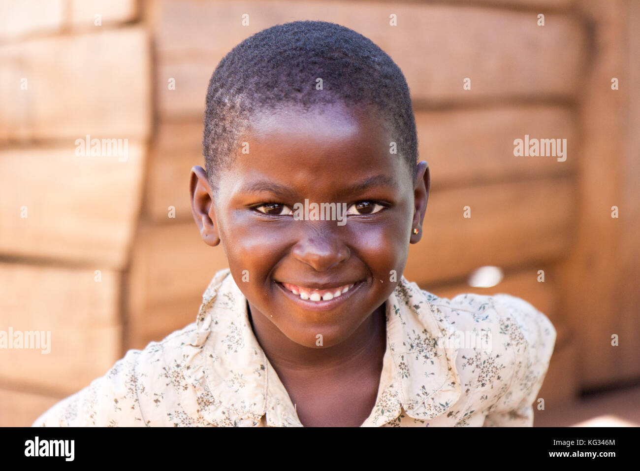 Ein lächelndes Mädchen vor eine Baracke aus Holz. Stockfoto