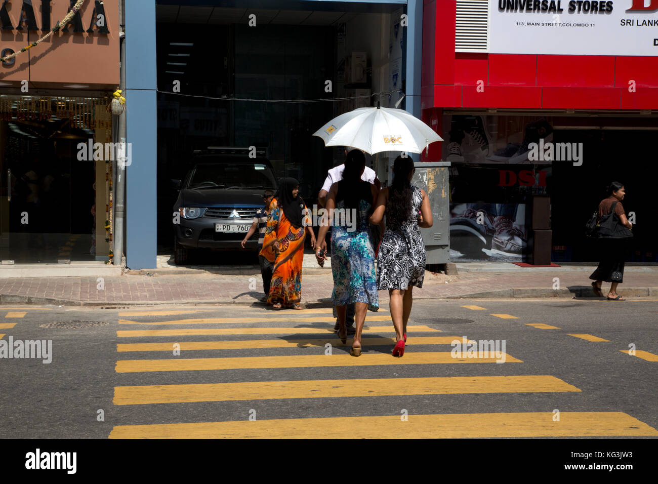 Die pettah Colombo Sri Lanka Hauptstraße Frauen Überschreiten der Straße mit Regenschirm für Schatten von der Sonne Stockfoto