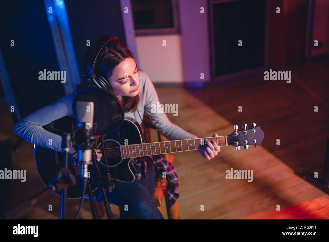 Frau artist Gitarre spielen in einem Tonstudio. Sängerin der Performance eines Songs im Studio. Stockfoto