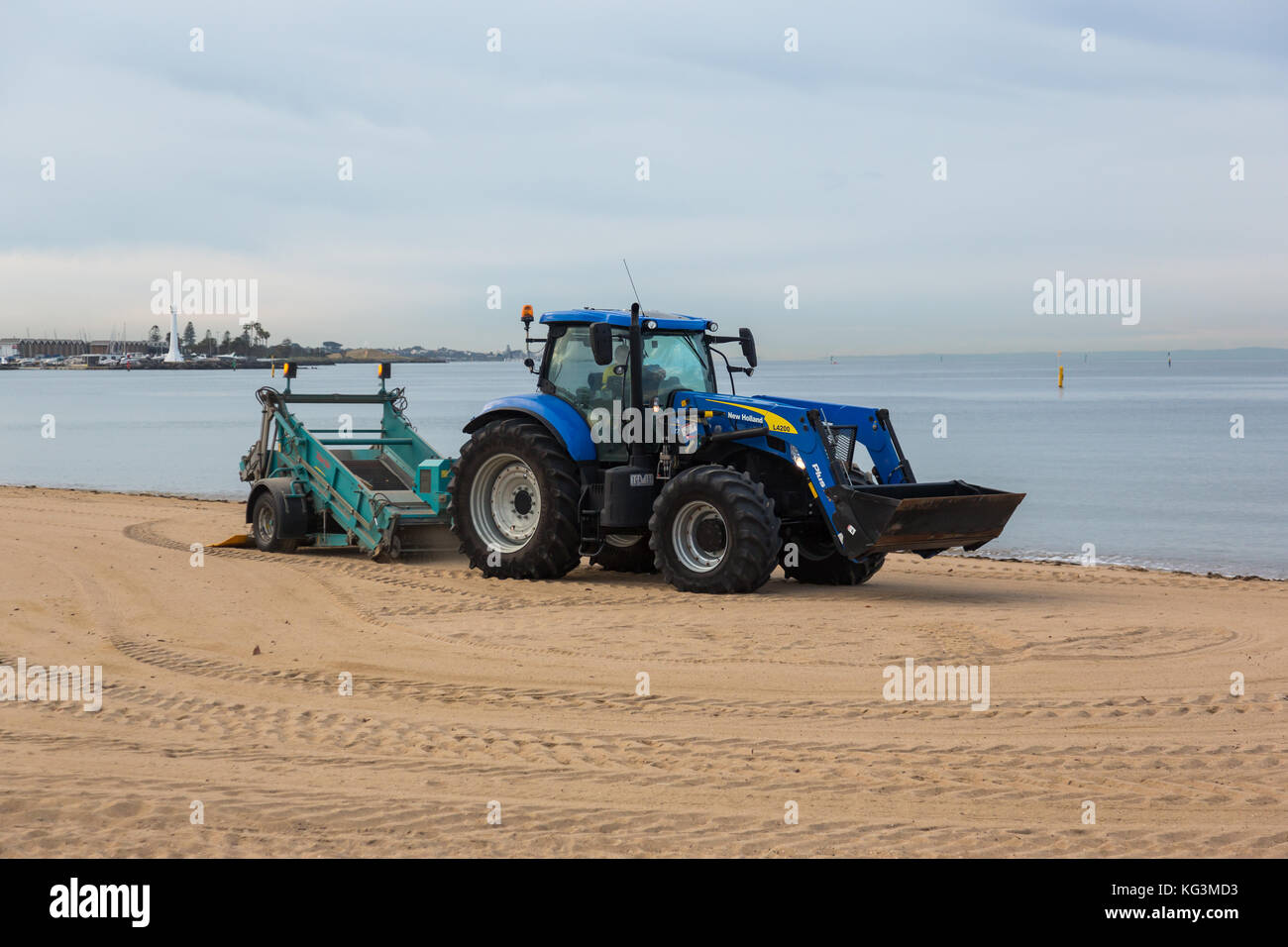 Ein Traktor Kämmen der Sand für Müll in St Kilda Strand, Victoria. Australien. Stockfoto