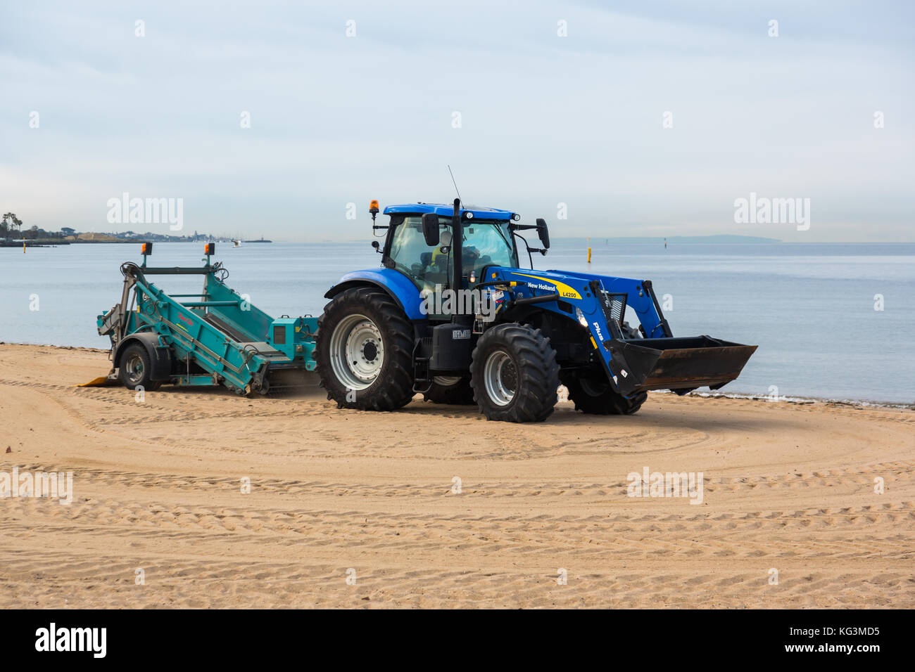 Ein Traktor Kämmen der Sand für Müll in St Kilda Strand, Victoria. Australien. Stockfoto