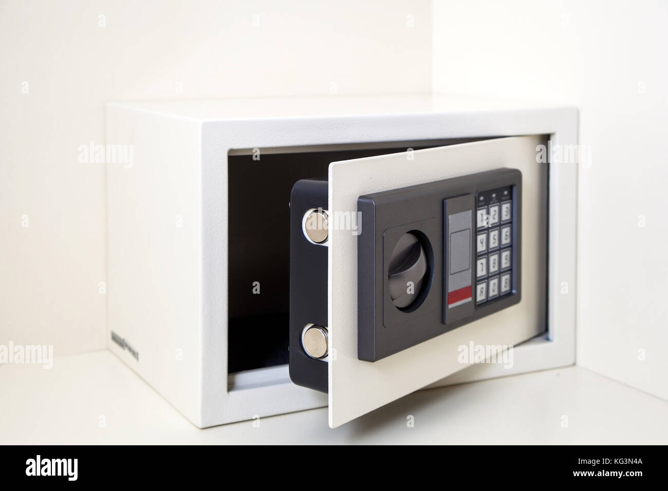 Eine Nahaufnahme eines kleinen Metallic white Safe mit Zahlenschloss für die Aufbewahrung von Wertsachen mit einem offenen Schrank mit weißer Tisch Stockfoto
