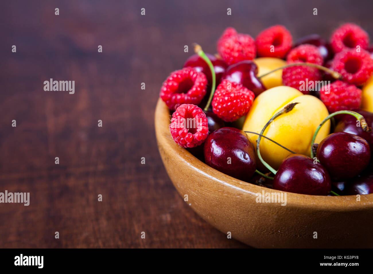 Reife Beeren in eine Platte auf einem Holztisch. Lecker und gesund Nachtisch Nahaufnahme, gesunde Ernährung. Stockfoto