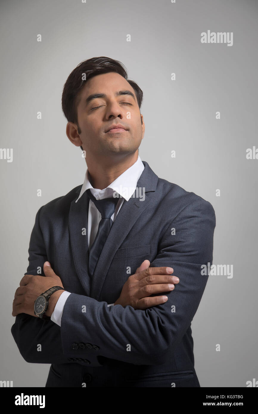 Junge Geschäftsmann schließen Augen mit gekreuzten Armen Stockfoto