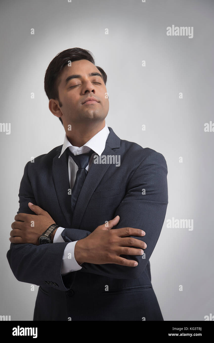 Junge Geschäftsmann schließen Augen mit gekreuzten Armen Stockfoto