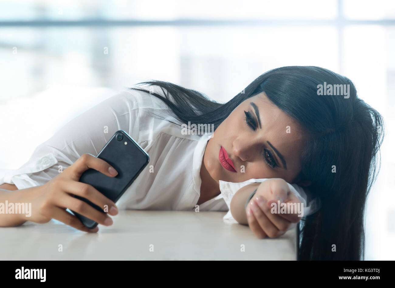 Geschäftsfrau, lehnend auf Tisch und mit Handy Stockfoto