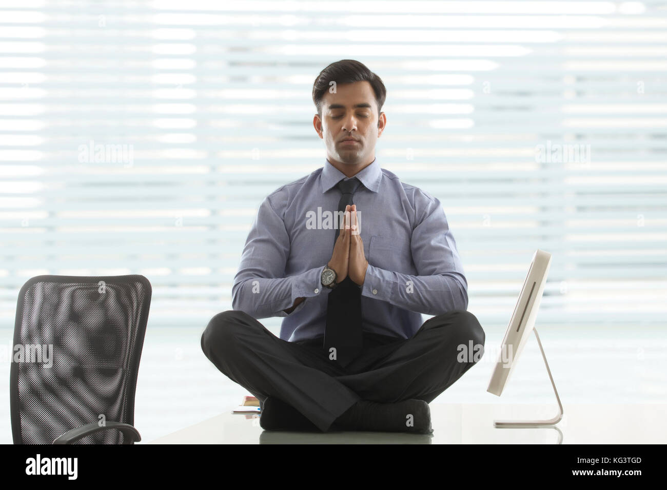 Geschäftsmann, Meditieren, auf dem Schreibtisch im Büro Stockfoto