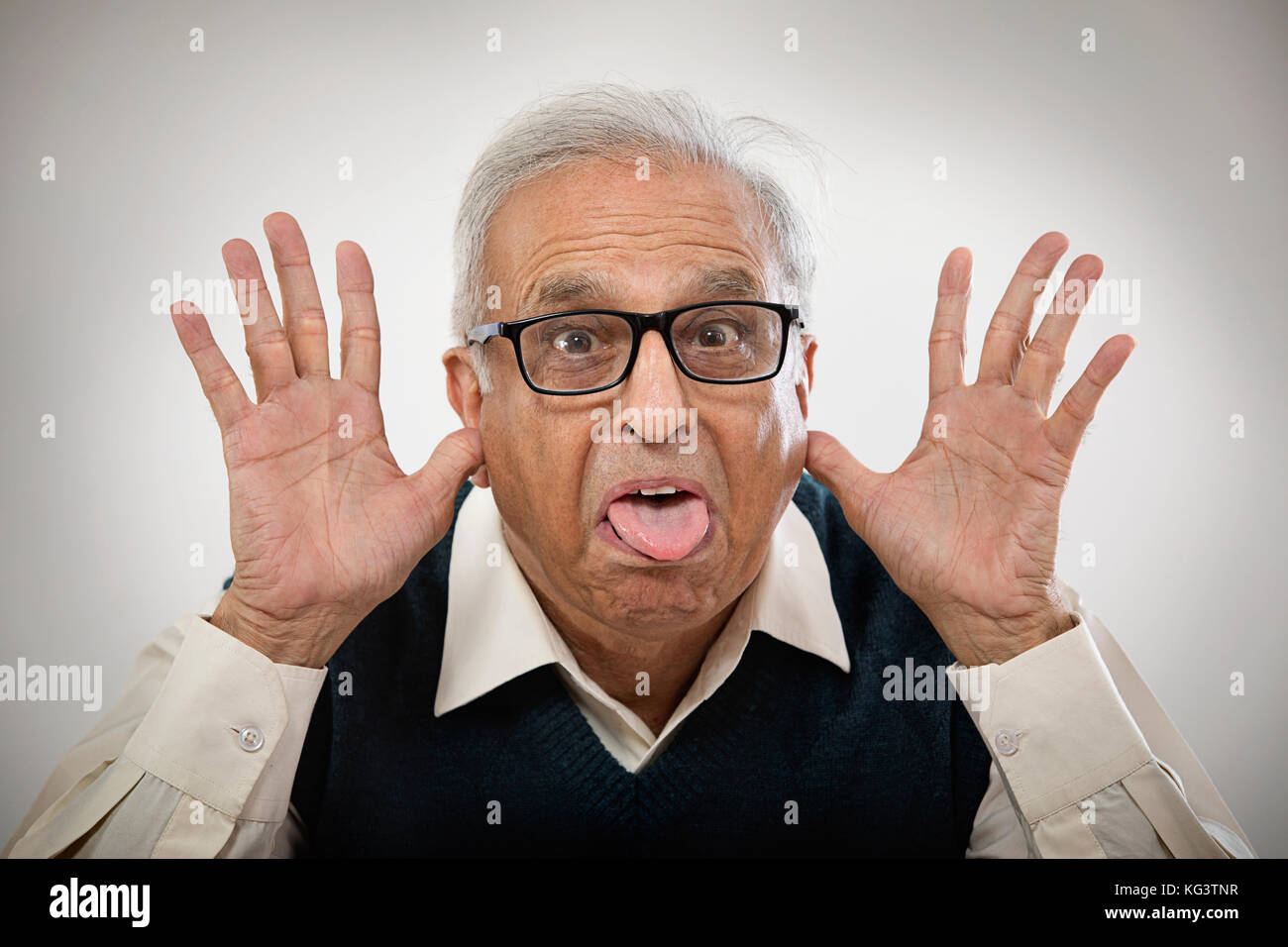 Älterer Mann mit Händen in den Ohren und die Zunge heraus, ein lustiges Gesicht Stockfoto
