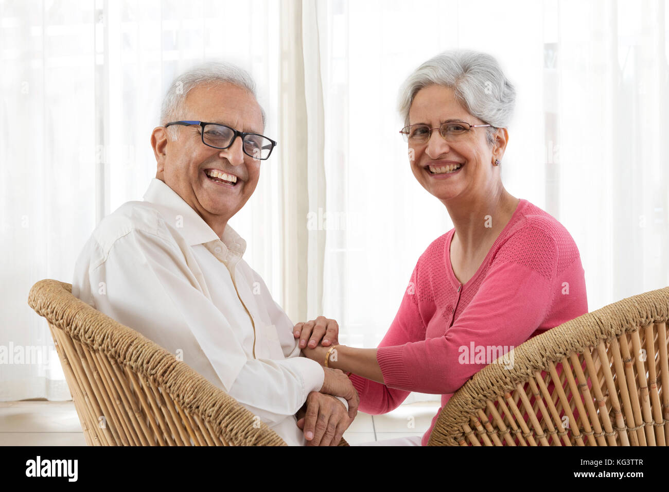 Portrait von Senior Paar lächelnd sitzen auf korbstuhl Stockfoto