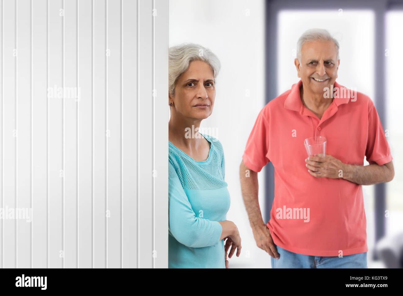 Älterer Mann hält Glas Wasser auf seine ältere Frau zu Hause Stockfoto