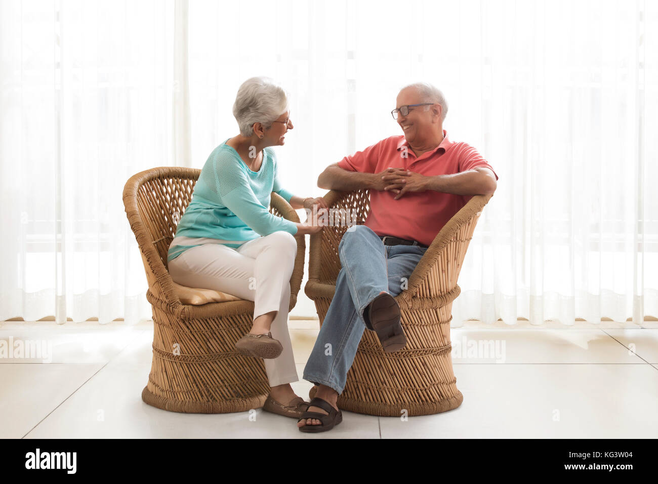 Senior Paar sitzt auf korbstuhl und Reden Stockfoto