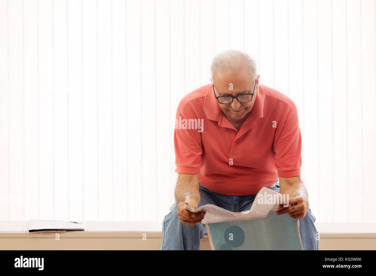 Älterer Mann lesen Zeitung auf der Werkbank zu Hause sitzen Stockfoto