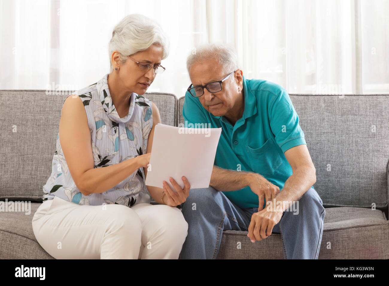 Älteres Ehepaar am Dokument sitzt auf einem Sofa auf der Suche Stockfoto