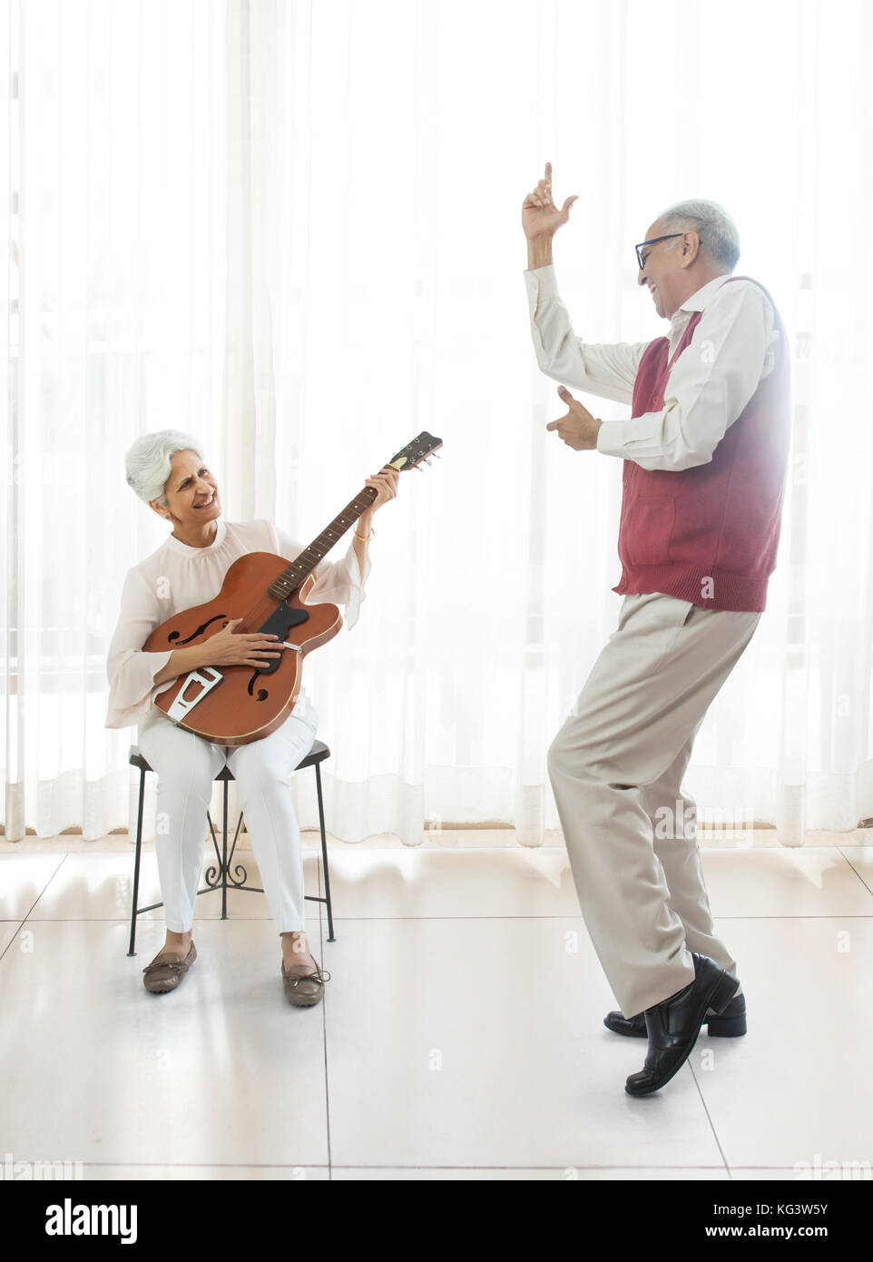 Ältere Frau spielt Gitarre und der ältere Mann tanzen Stockfoto