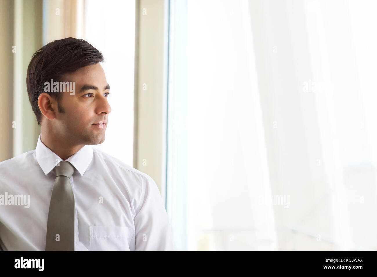 Portrait von zuversichtlich Geschäftsmann Blick aus Fenster Stockfoto