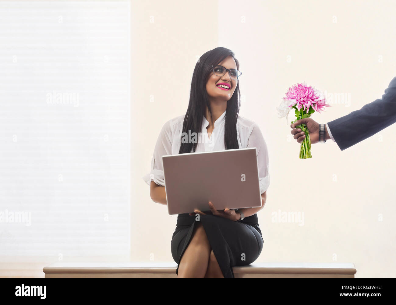 Geschäftsmann mit Blumenstrauß zu Kollegin im Büro Stockfoto