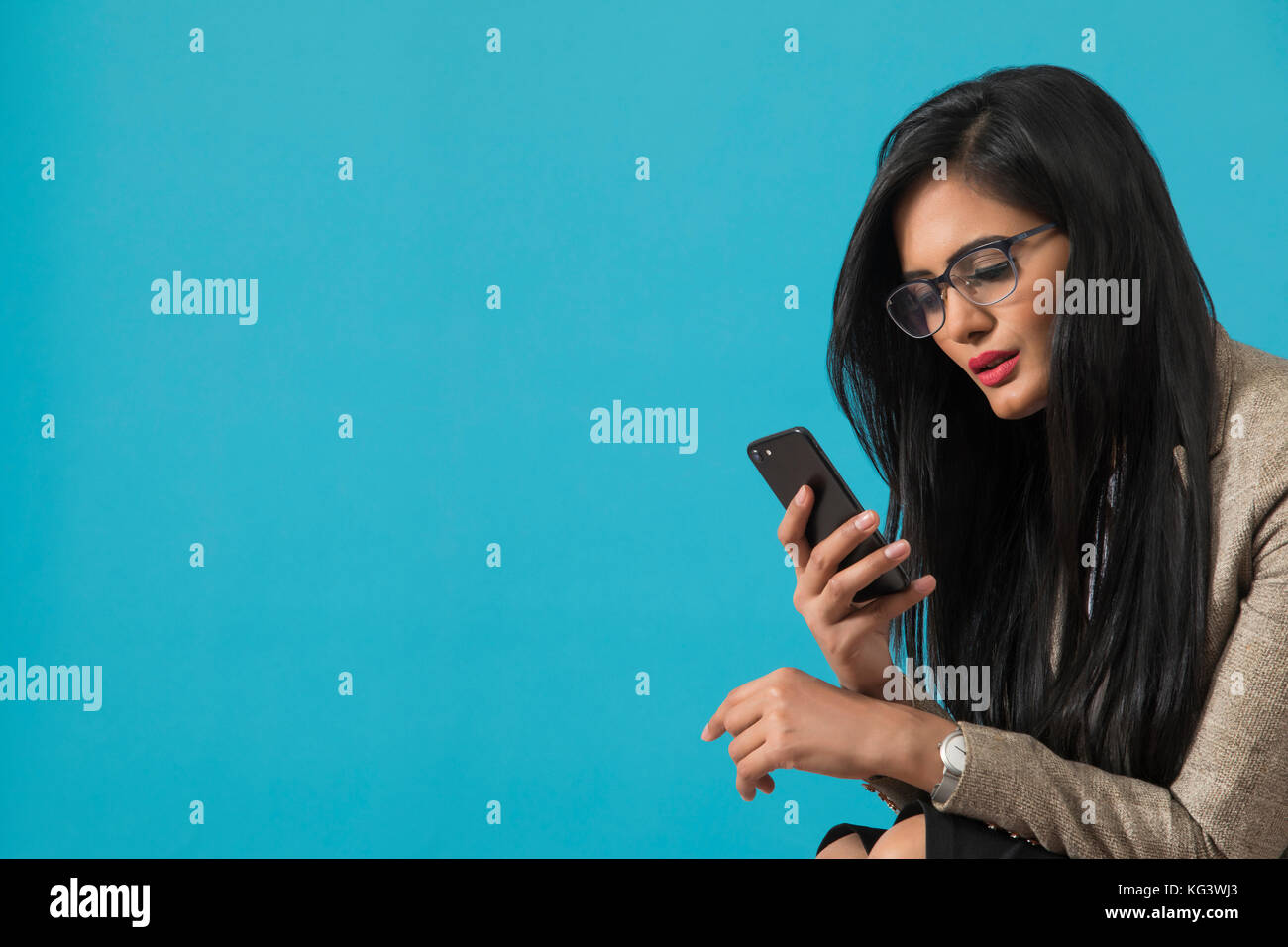 Geschäftsfrau mit smart phone vor blauem Hintergrund Stockfoto