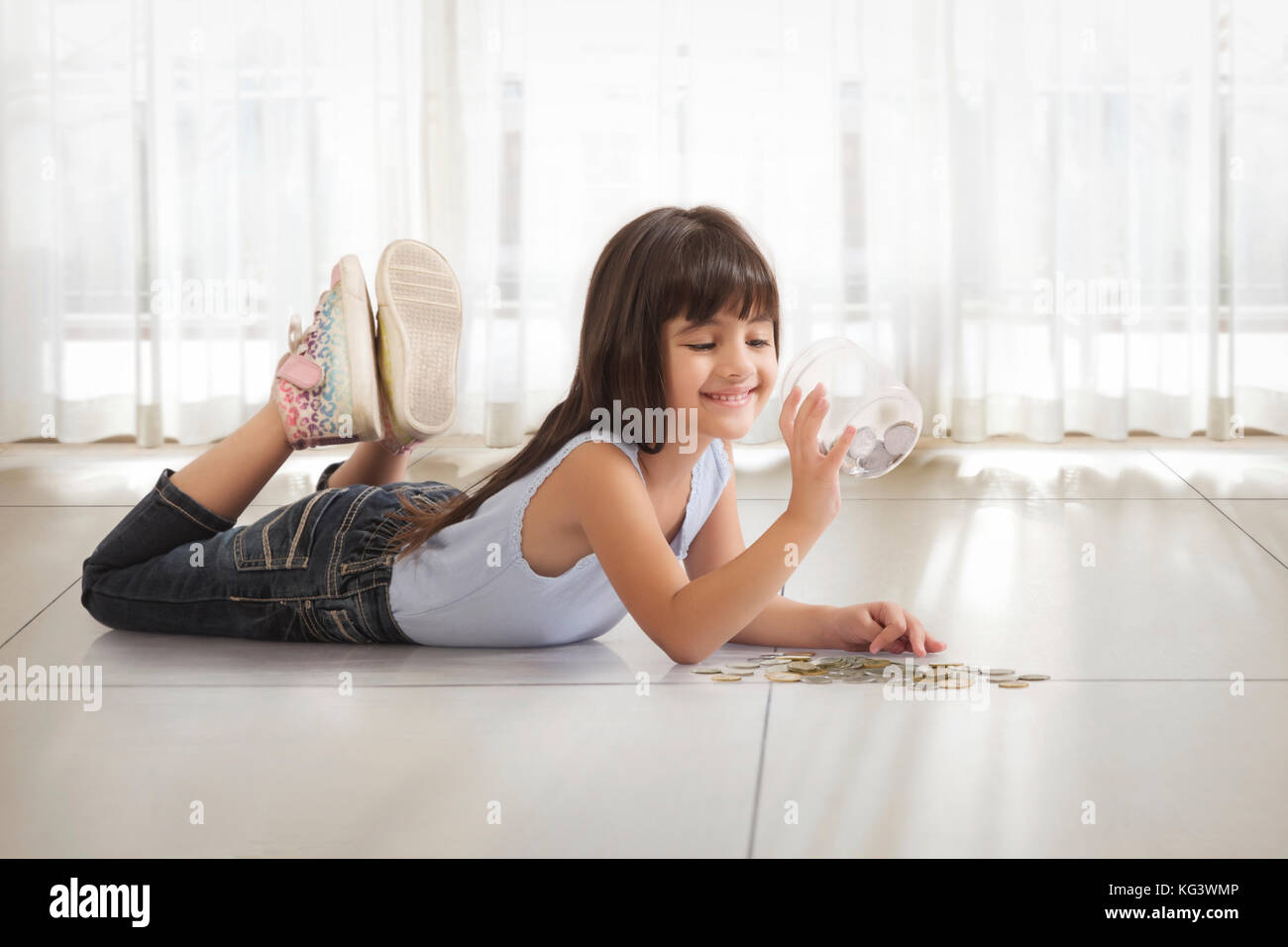 Kleines Mädchen liegt auf dem Boden in Geld, Stockfoto