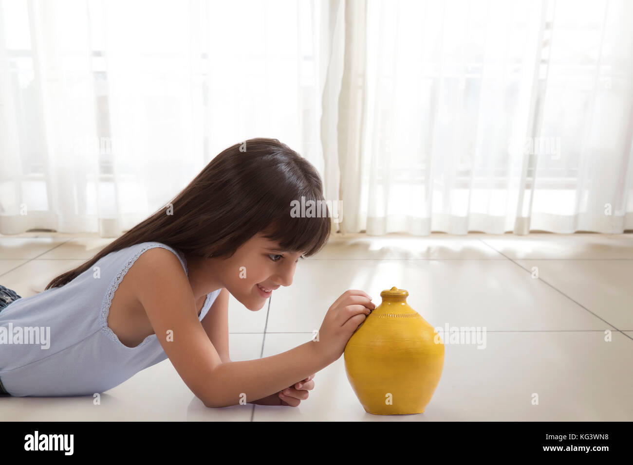 Kleines Mädchen liegt auf dem Boden und die Münze in Ton piggy Bank Stockfoto