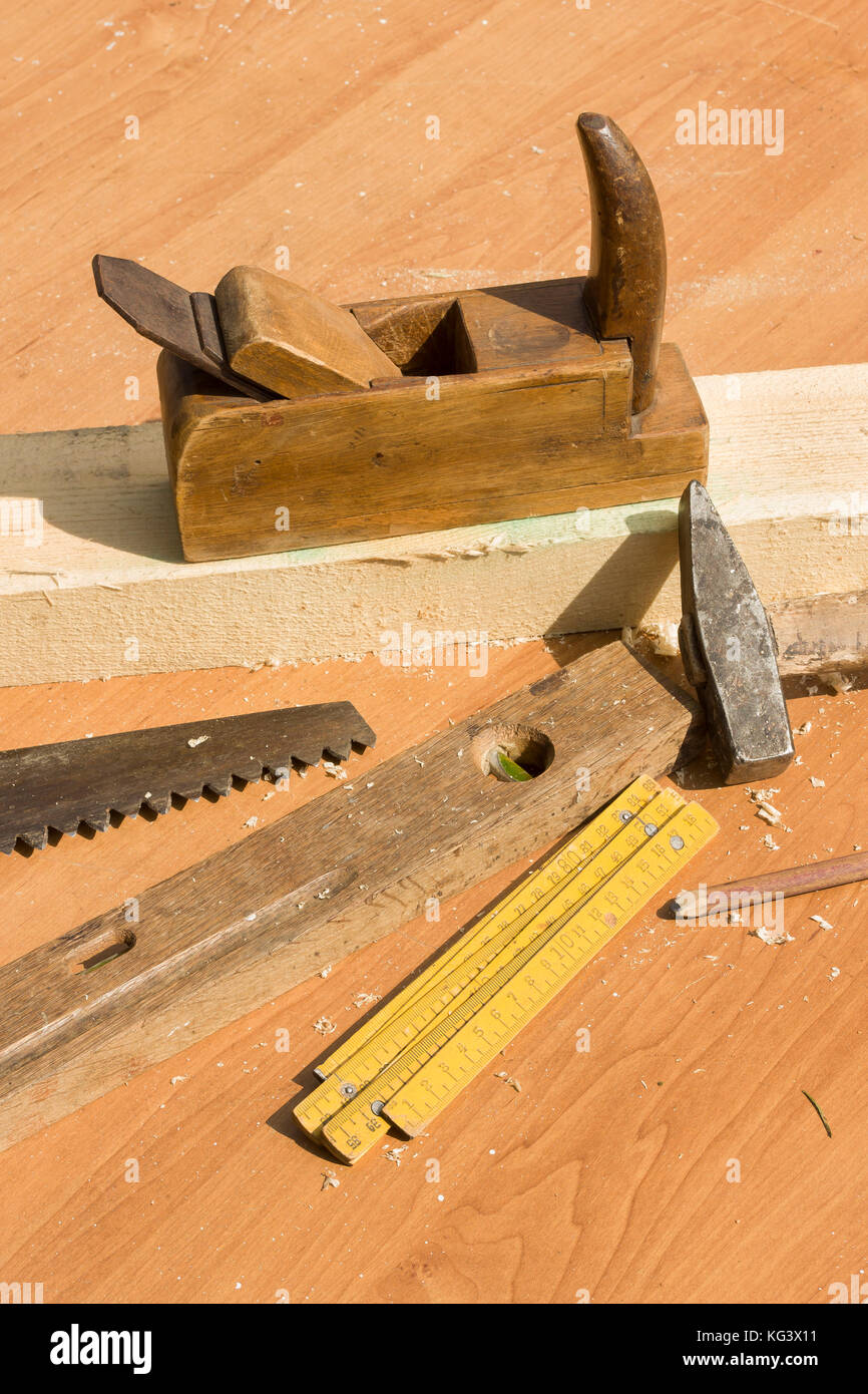 Alte tischlerei Werkzeuge liegen auf dem Tisch. Alte Tischler Werkzeuge auf dem Tisch liegen. Ebene, Säge, Ebene, Schaufel, Hammer, Bleistift, das alte Flugzeug steht auf dem Tabl Stockfoto