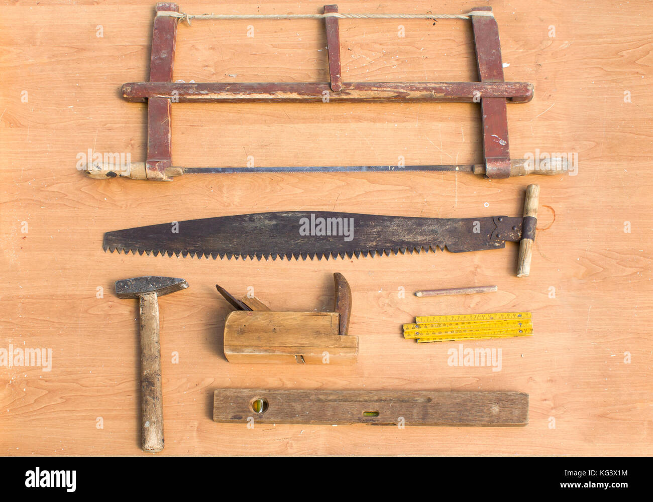 Alte Tischler Werkzeuge auf dem Tisch liegen. Ebene, Säge, Ebene, Schaufel, Hammer, Bleistift. Alte tischlerei Werkzeuge liegen auf dem Tisch. Stockfoto