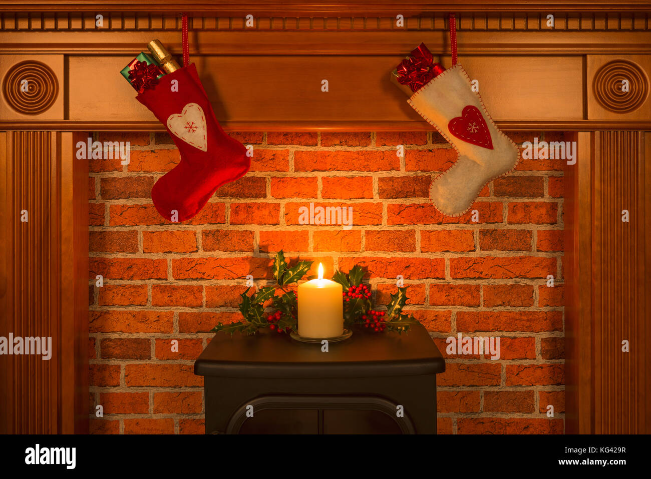 Zwei Weihnachtsstrumpf hängt über einem Kamin mit Geschenken und eine Kerze. Stockfoto